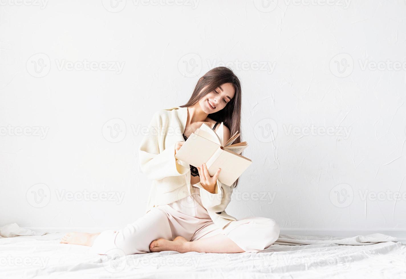 woman in comfortable home clothes reading a book sitting on the floor photo