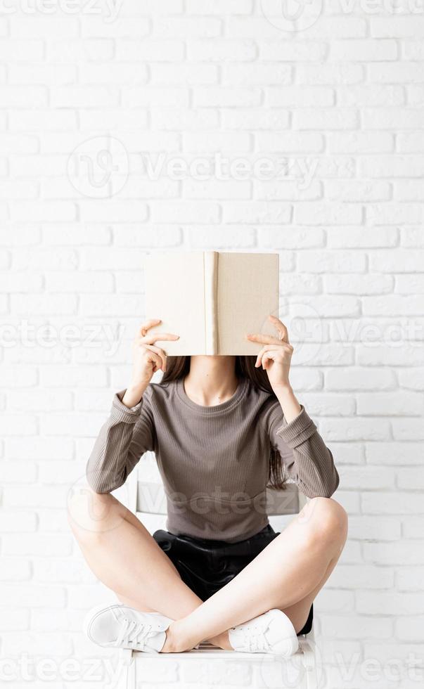 Woman sitting on the chair with legs crossed reading a book photo