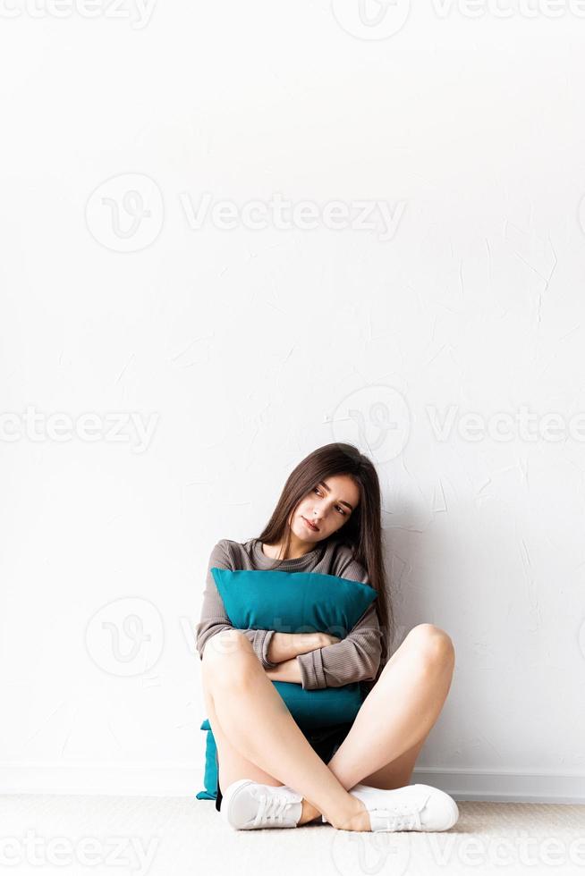 Mujer en ropa casual sentada en el suelo con almohadas foto