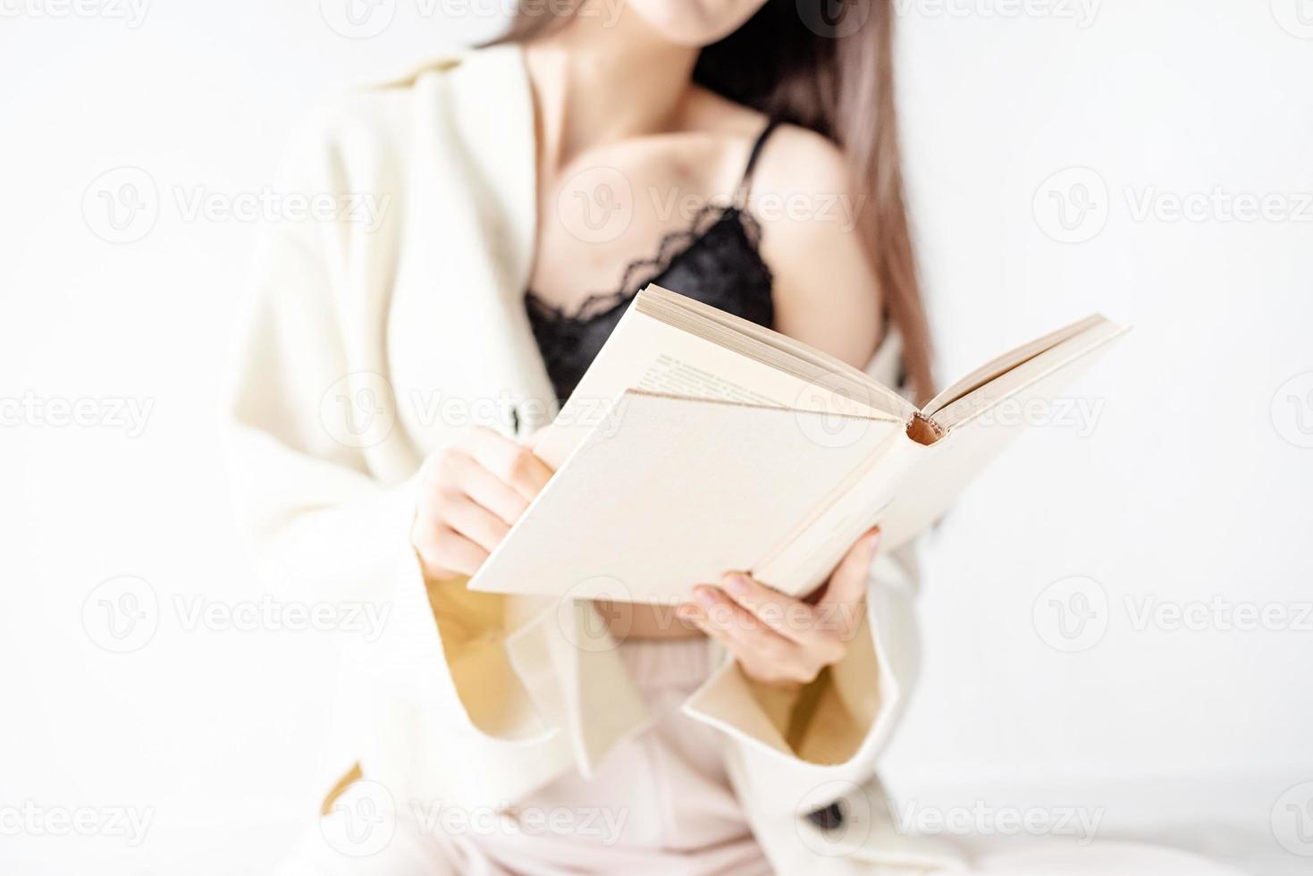 Mujer en ropa de casa cómoda leyendo un libro sentado en el suelo foto