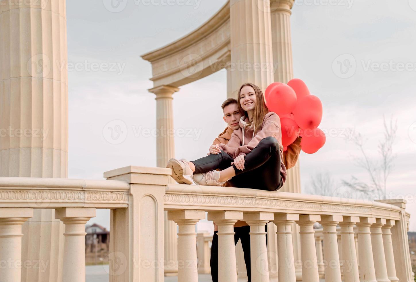 couple embracing each other outdoors in the park holding balloons photo