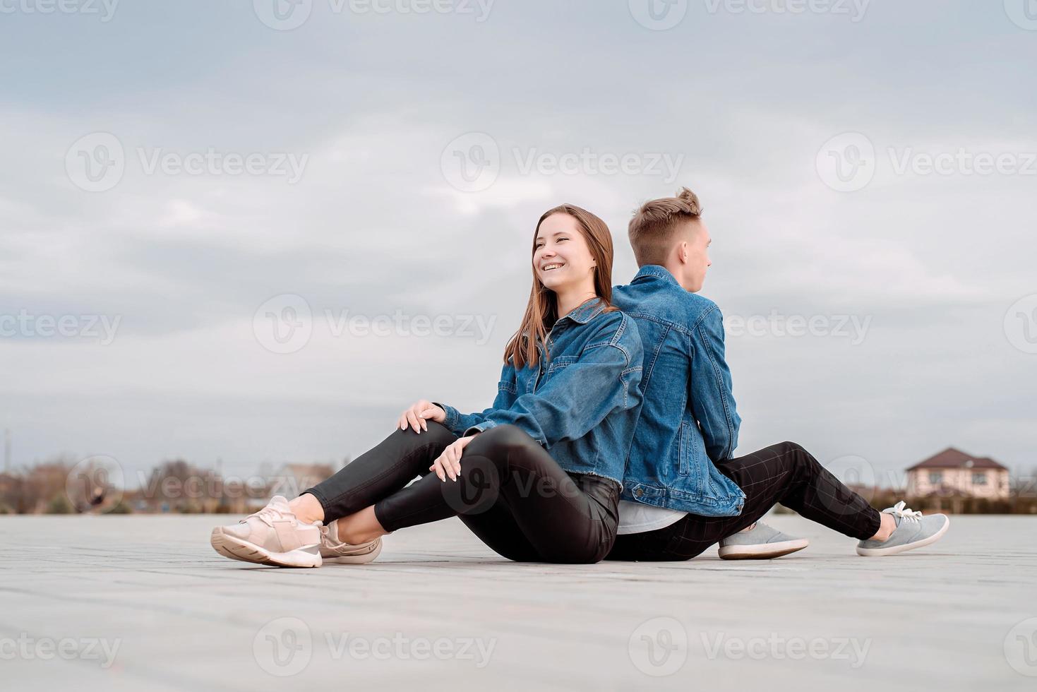 couple sitting back to back in the street spending time together photo