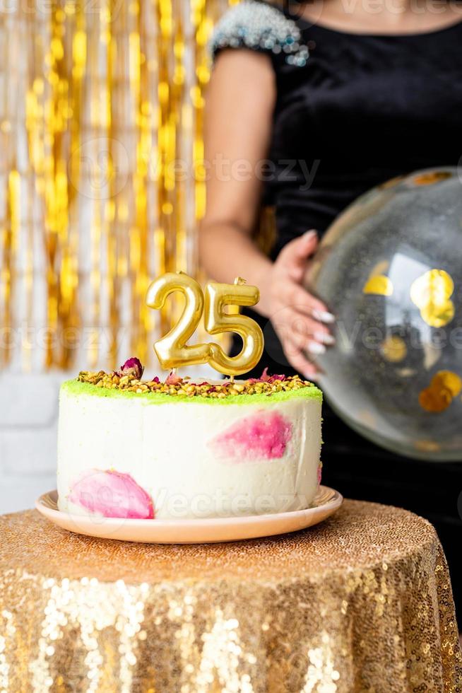 Velas de oro 25 en tarta de cumpleaños sobre fondo dorado brillo foto