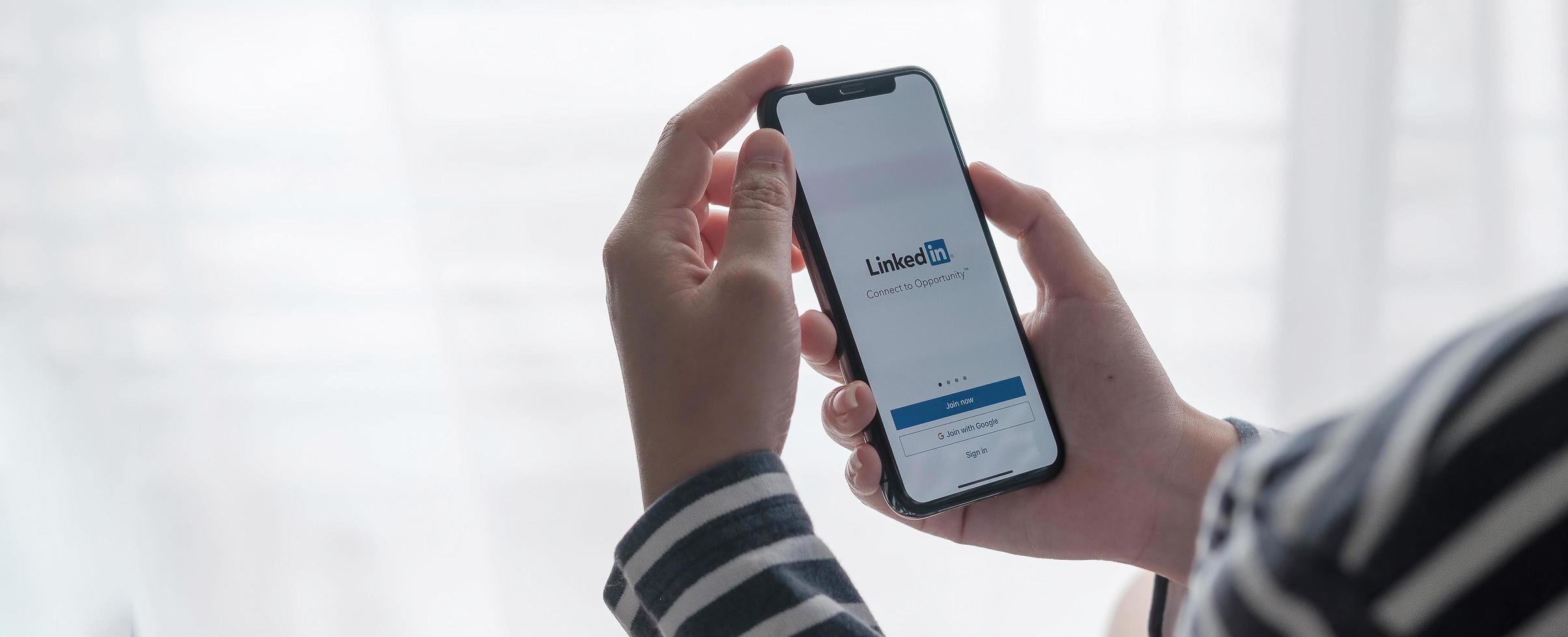 chiang mai, tailandia 2021: una mujer sostiene el iphone xs de apple con la aplicación de linkedin en la pantalla. foto