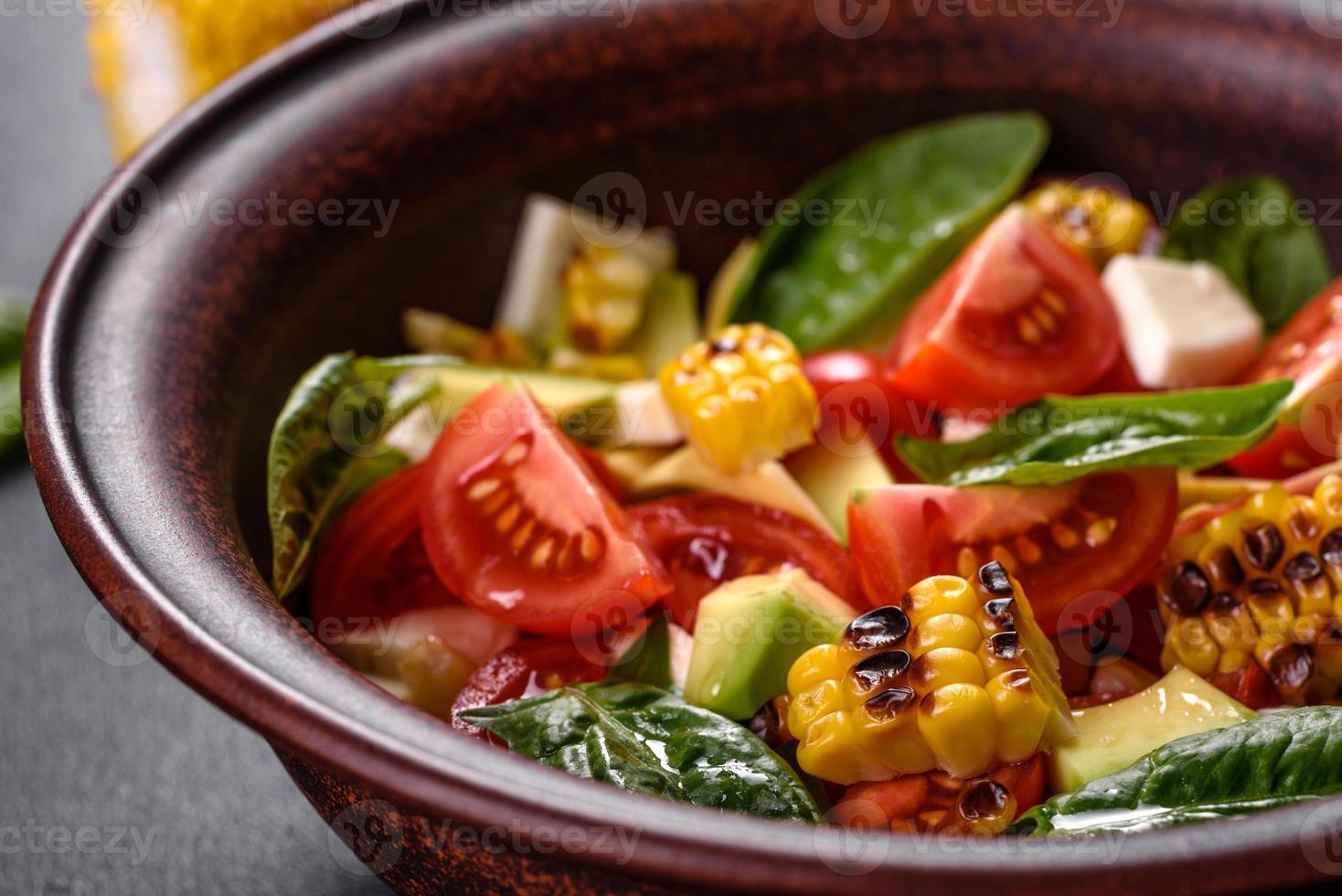 Delicious fresh salad with tomatoes, avocado, cheese and grilled corn photo