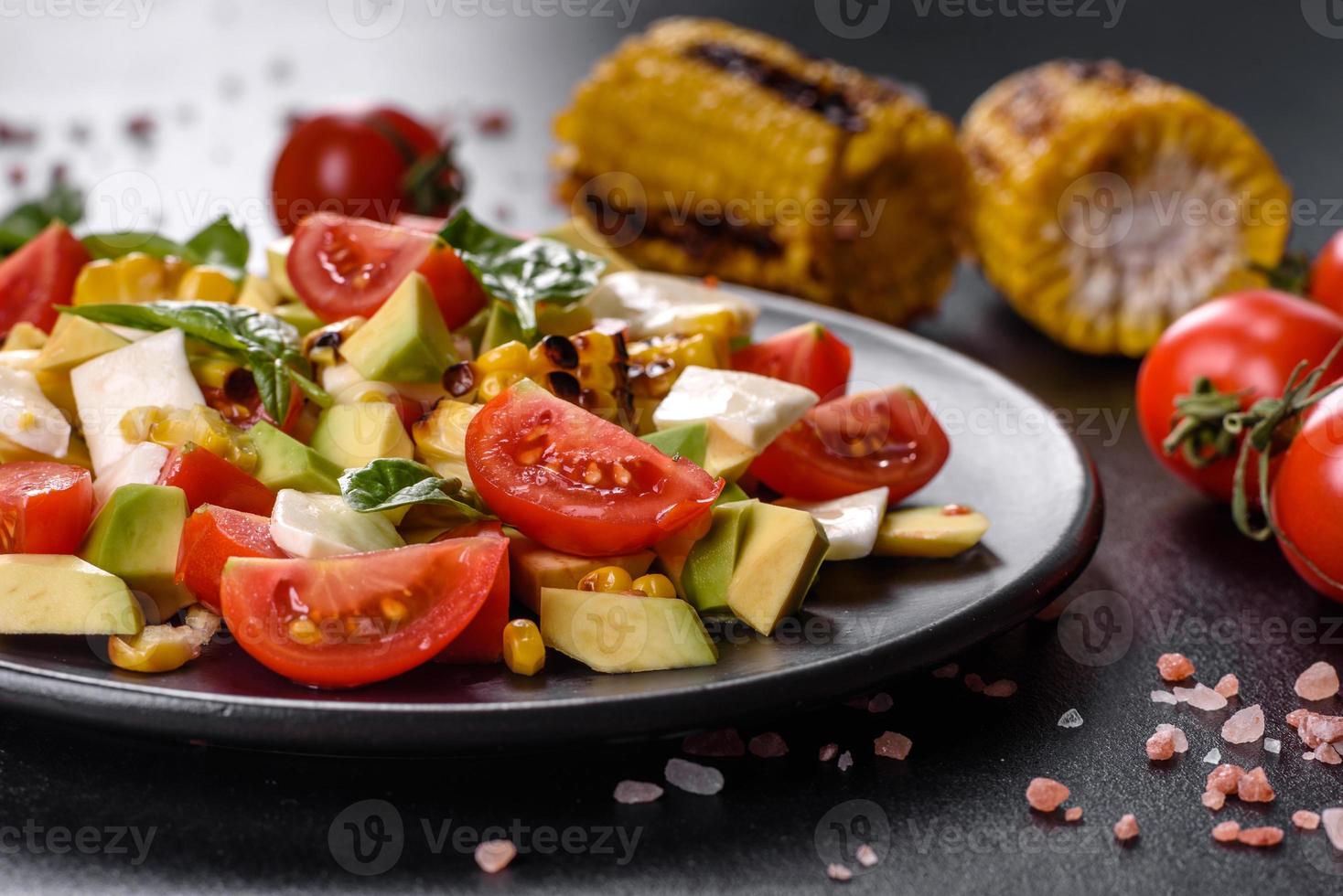 Delicious fresh salad with tomatoes, avocado, cheese and grilled corn photo