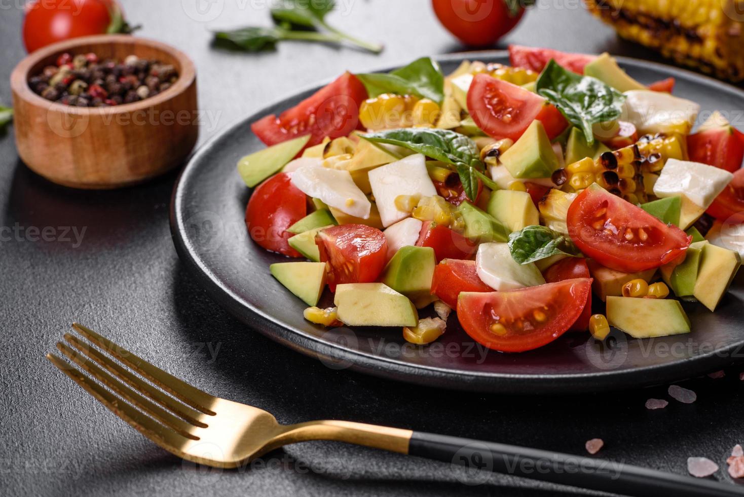 Delicious fresh salad with tomatoes, avocado, cheese and grilled corn photo