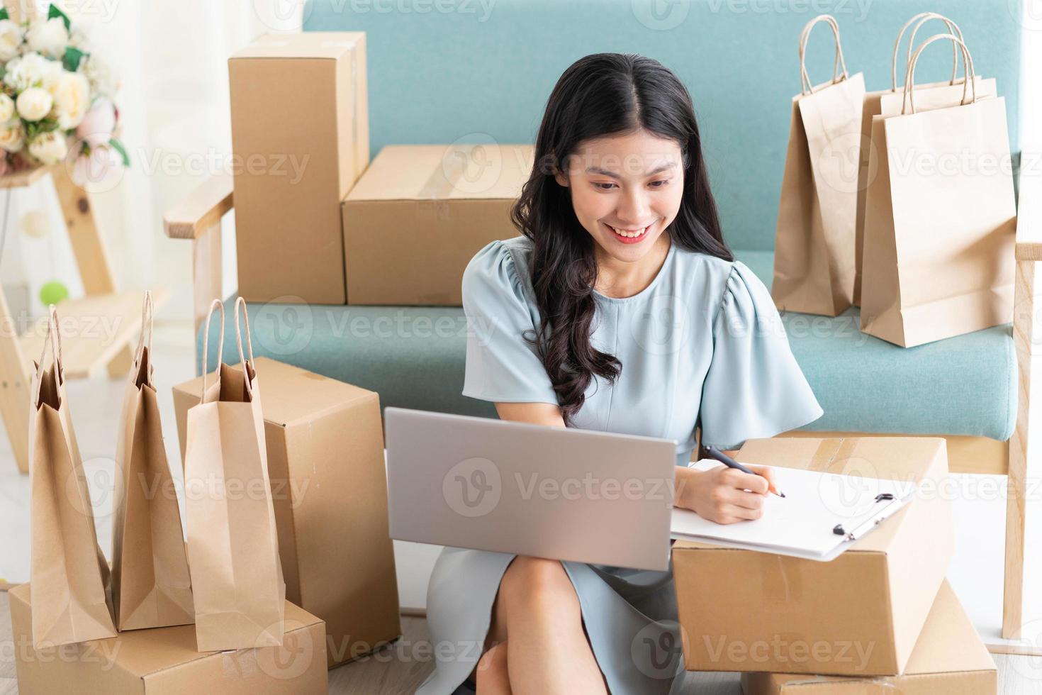 joven asiática sentada en casa vendiendo en línea foto