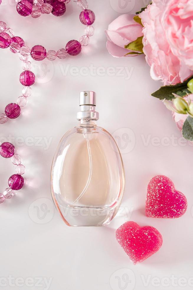 botella de perfume, flores y corazones sobre un fondo claro foto