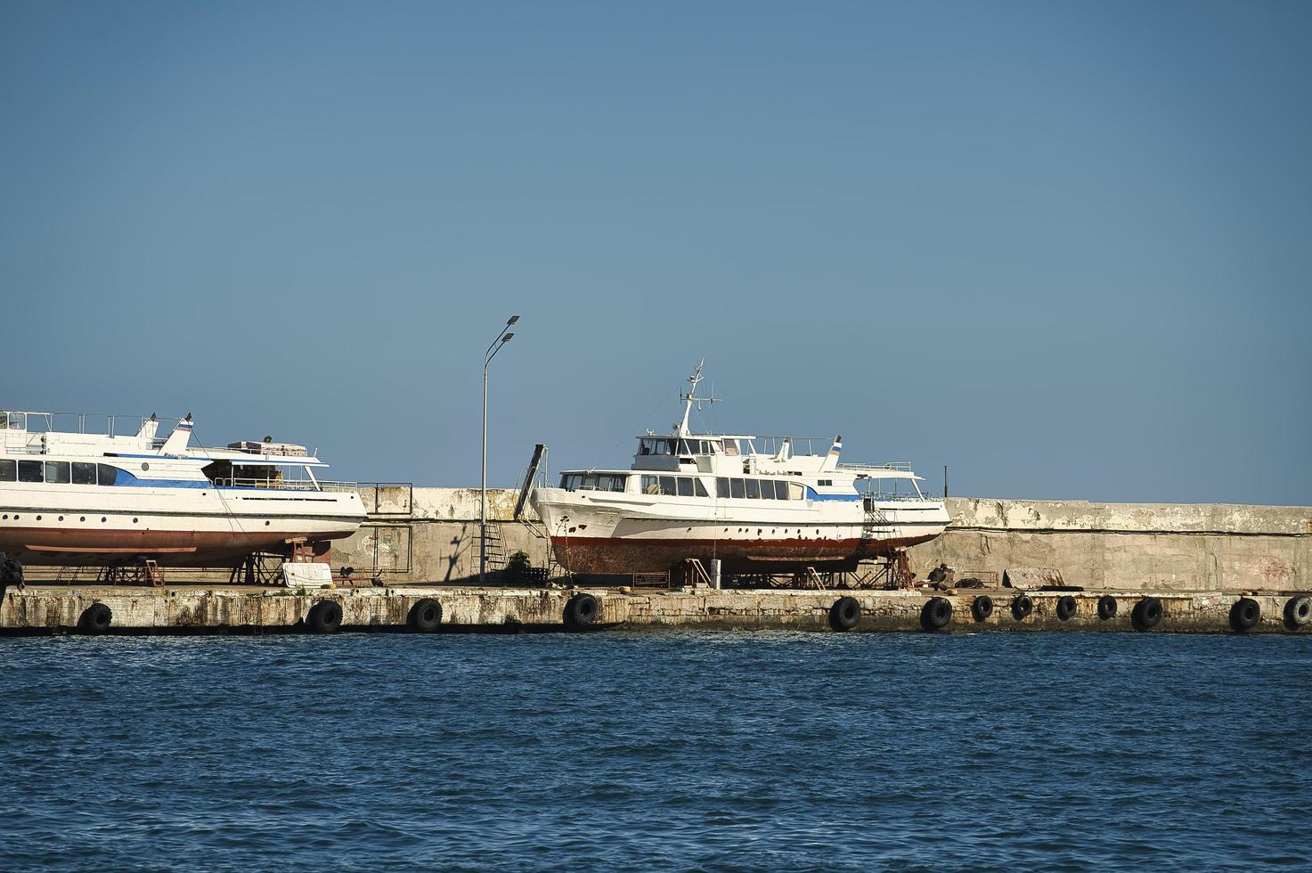 Seascape with a pier in Yalta and old boats in the parking lot photo