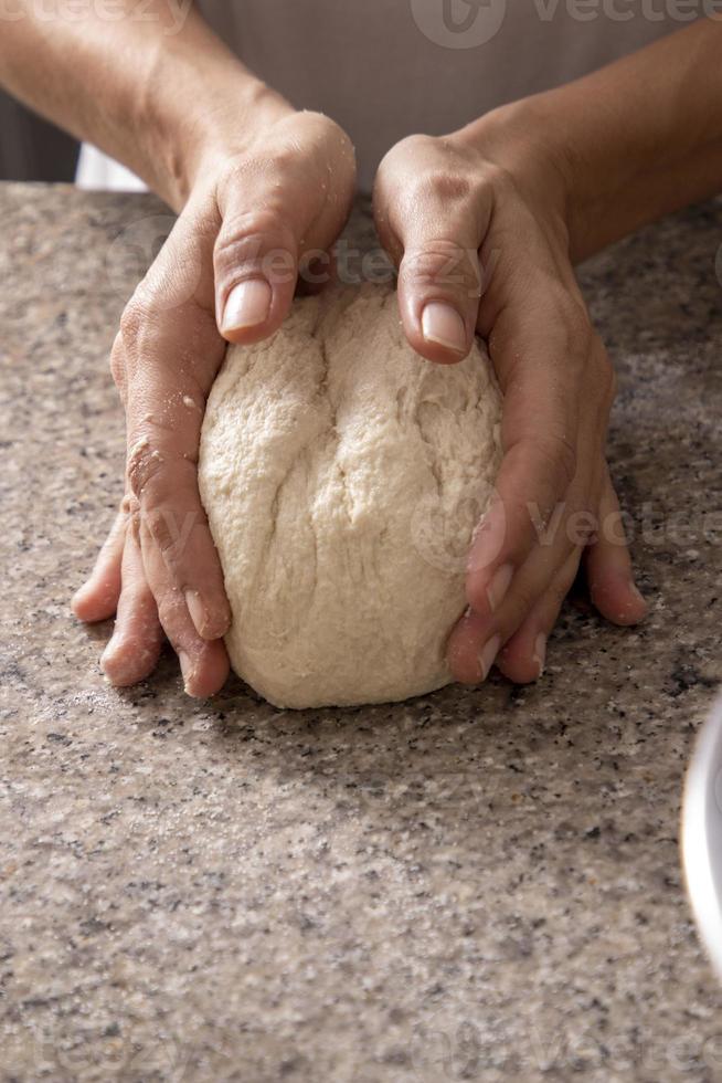 manos de mujer amasando pizza foto