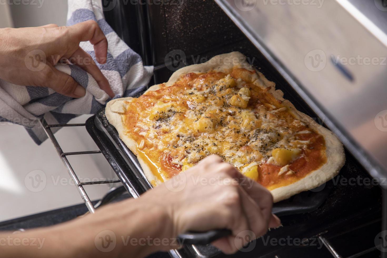 manos de mujer sacando pizza del horno foto