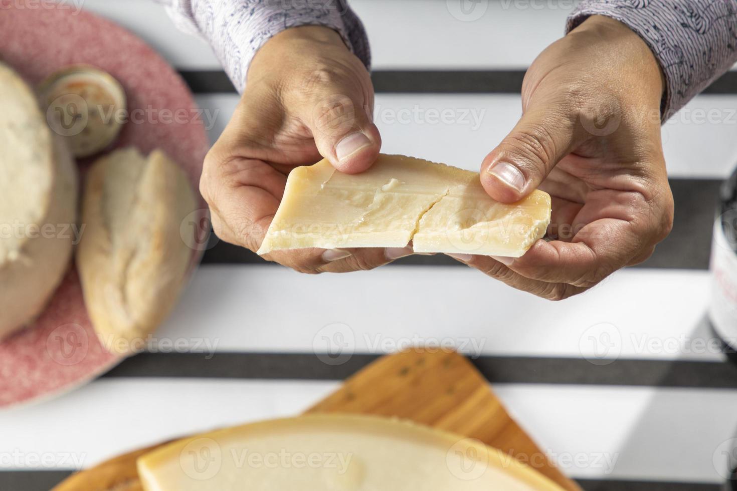 Primer plano de manos rompiendo el queso parmesano foto