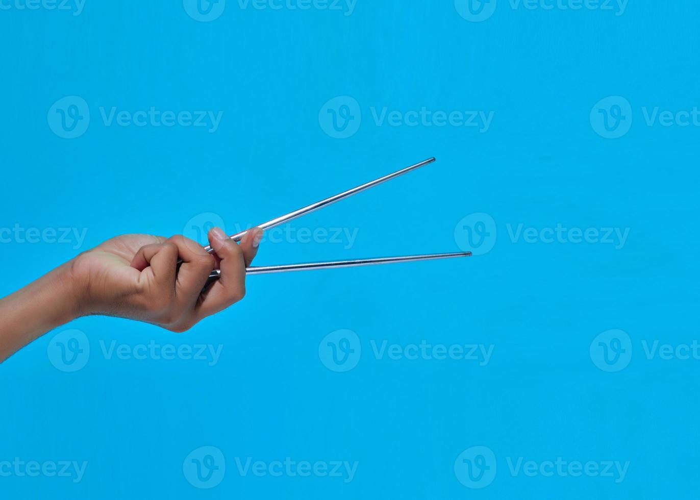closeup of human hand showing movement will give 2 iron chopsticks. photo
