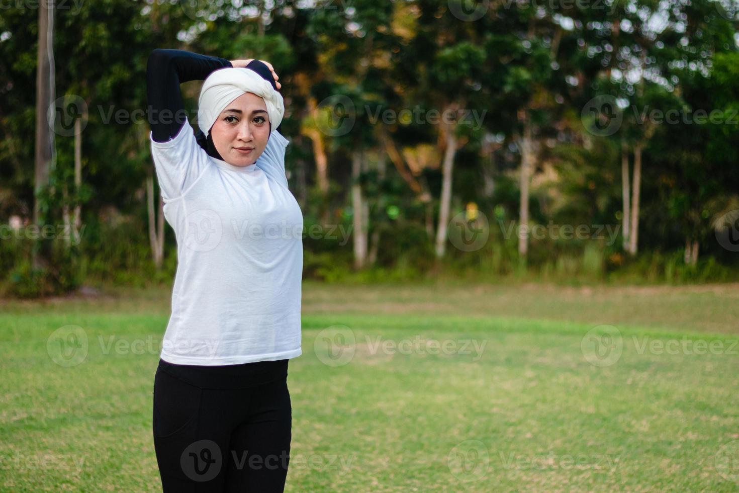 Pleasant woman in hijab and sportswear doing yoga and stretching. photo