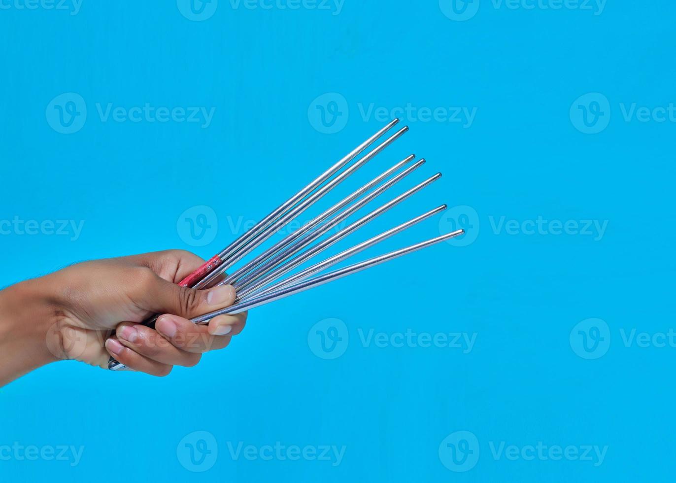 El primer plano de la mano humana que muestra el movimiento dará unos palillos de hierro. foto