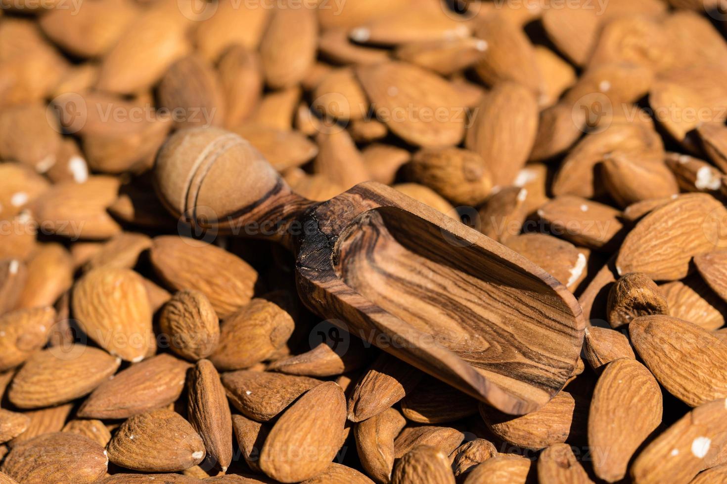 un montón de almendras y un vaso con aceite de almendras foto