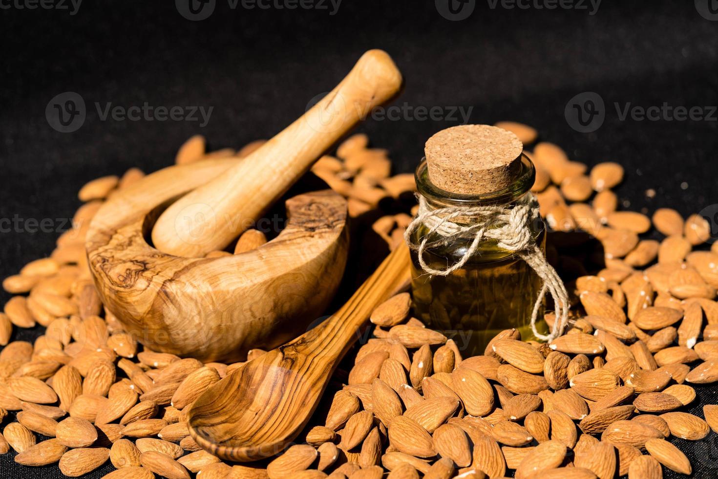 un montón de almendras y un vaso con aceite de almendras foto