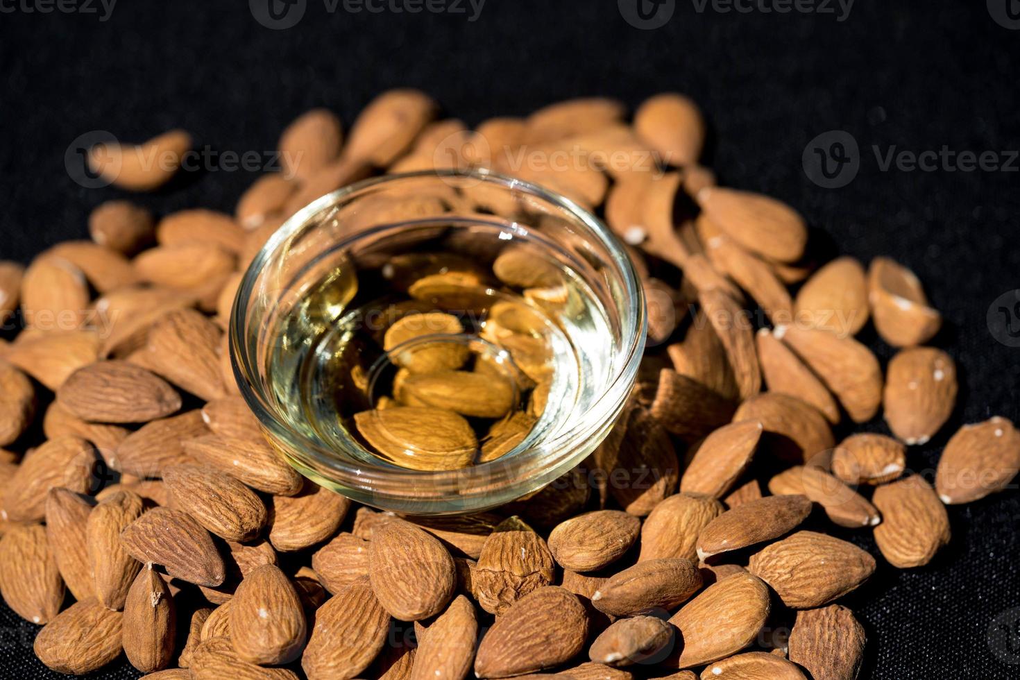 a pile of almonds and a glas with almond oil photo