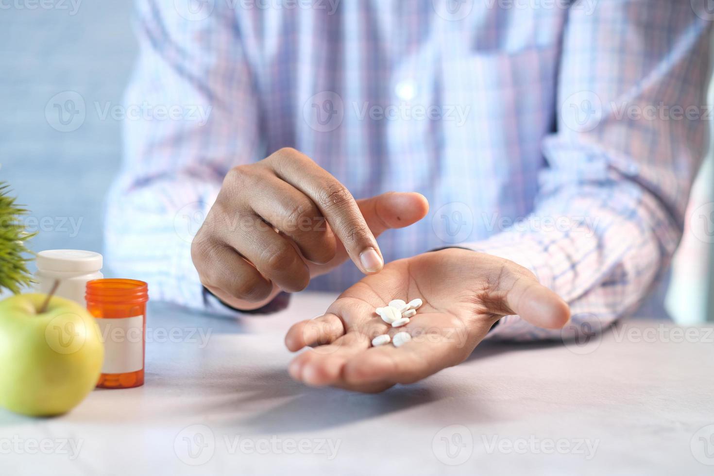 man's hand with medicine spilled out of the pill container while sited photo