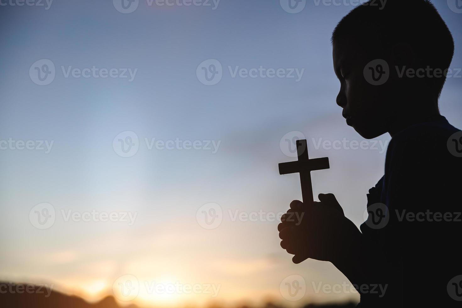 silueta, de, niño, rezando, con, cruz, en, naturaleza, amanecer foto