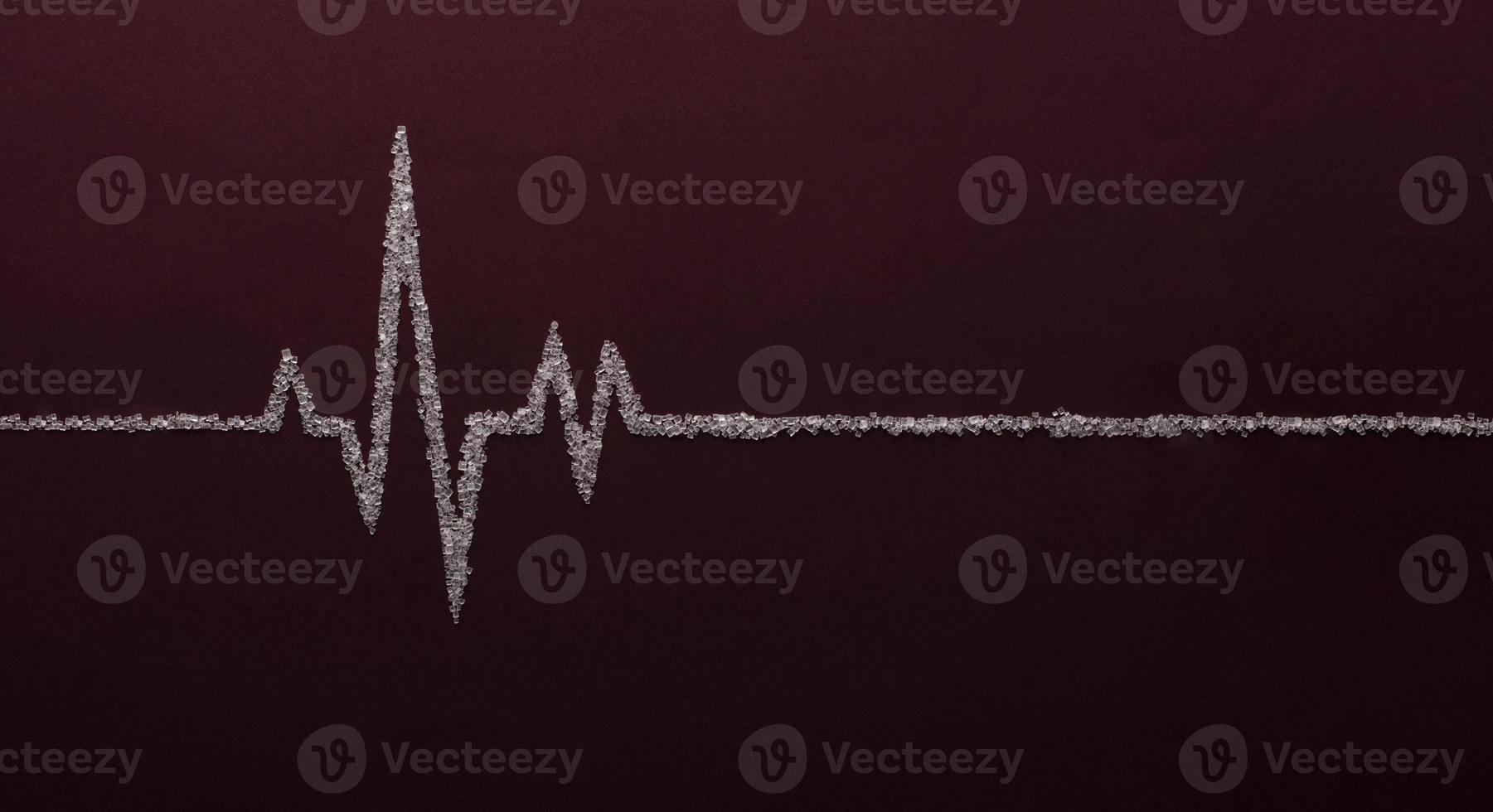 Heart rate graph using white sugar on red background photo