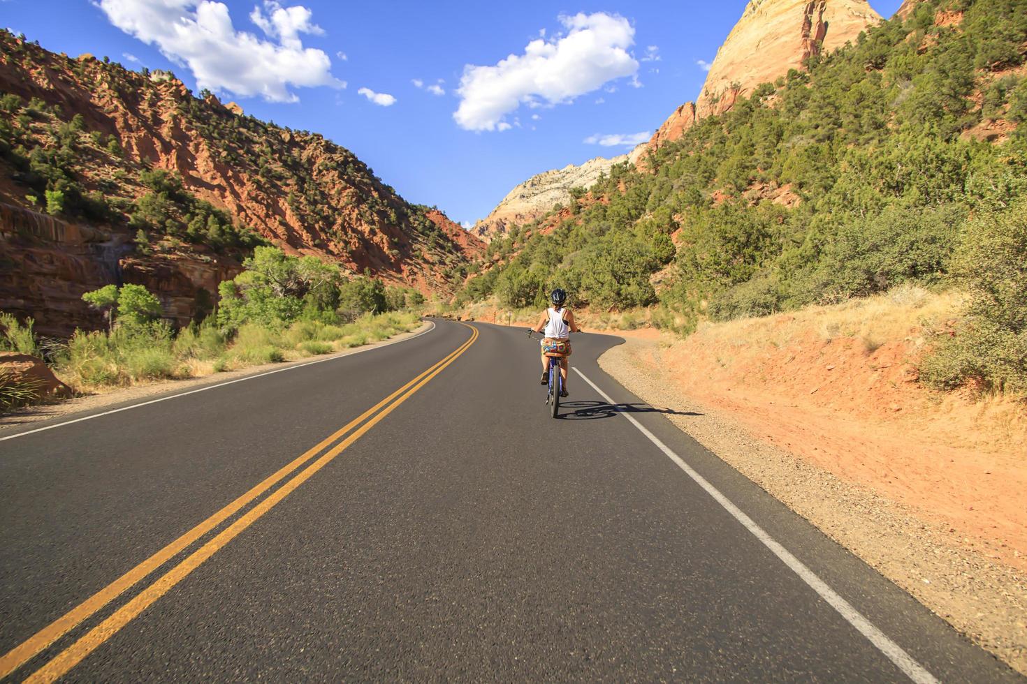 mujer en bicicleta en una carretera a través del desierto foto