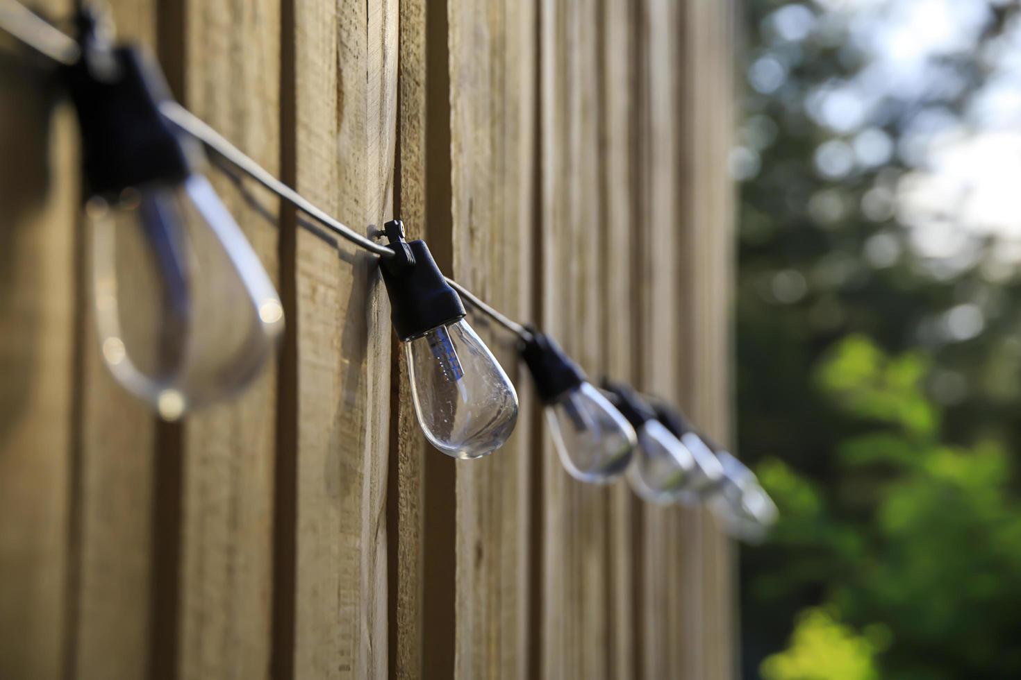 Row of lightbulbs hanging on an outdoor fence photo