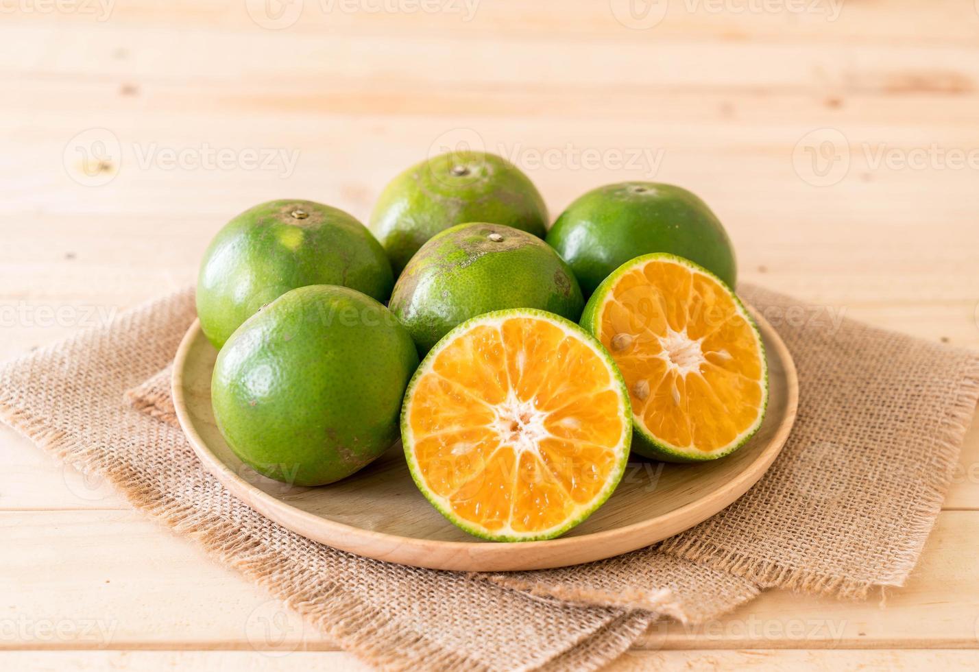 Naranja fresca en placa de madera sobre la mesa foto