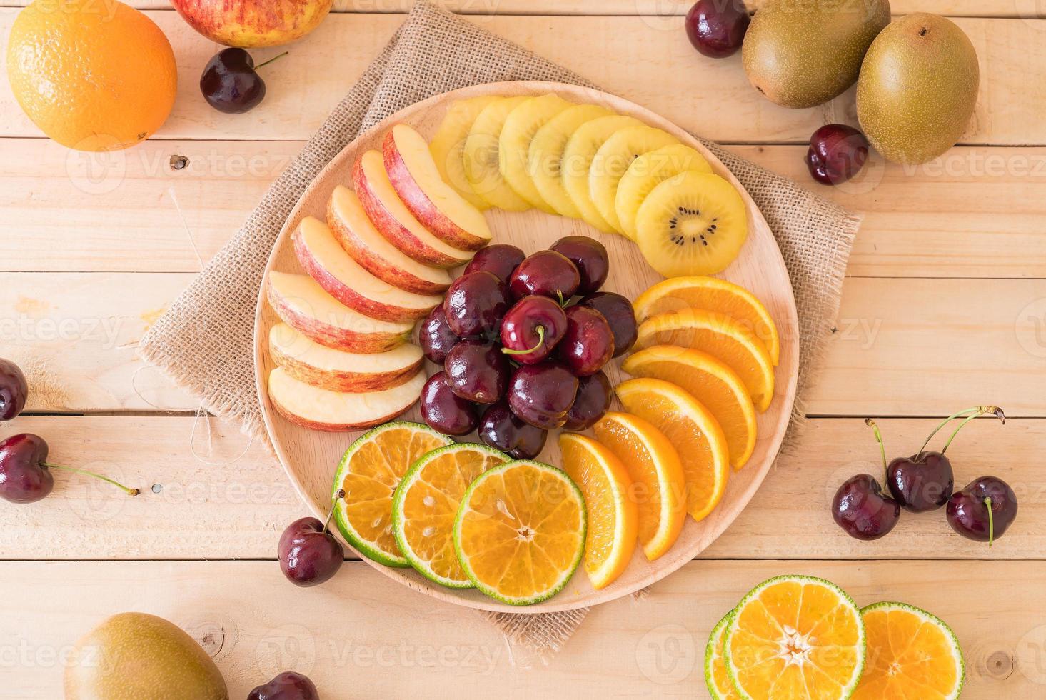 Mixed sliced fruit in wood plate photo