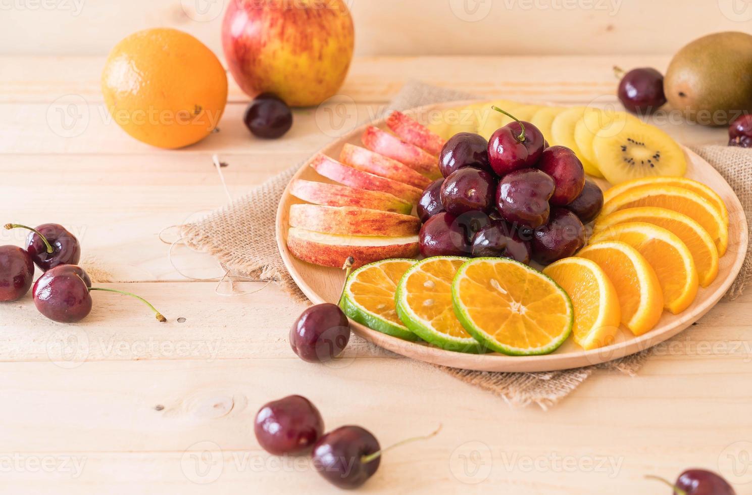 Mixed sliced fruit in wood plate photo