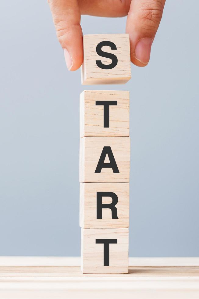 Hand holding wooden block with START text photo