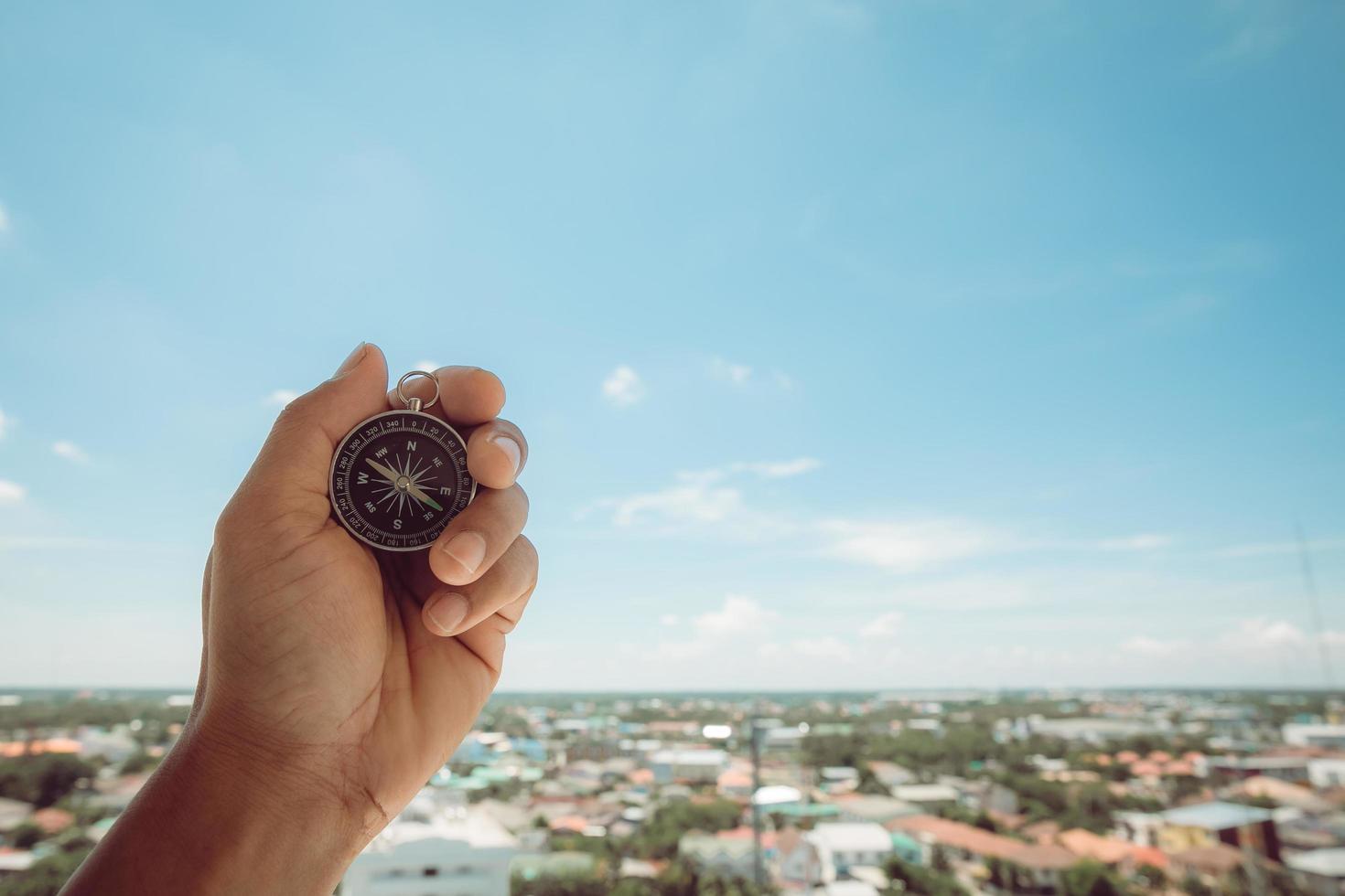 Male hands holding a compass on the sky background photo