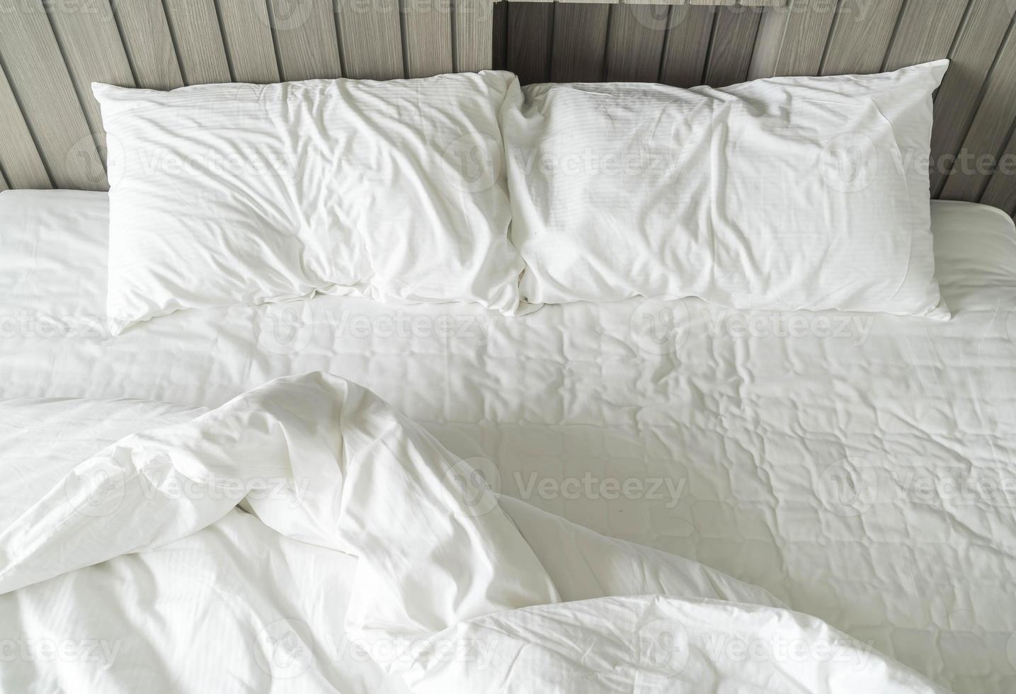Cama con borde con decoración de almohada desordenada blanca en el interior del dormitorio foto