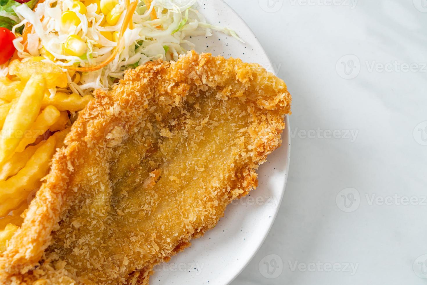 Fried fish fillet and potatoes chips with mini salad photo