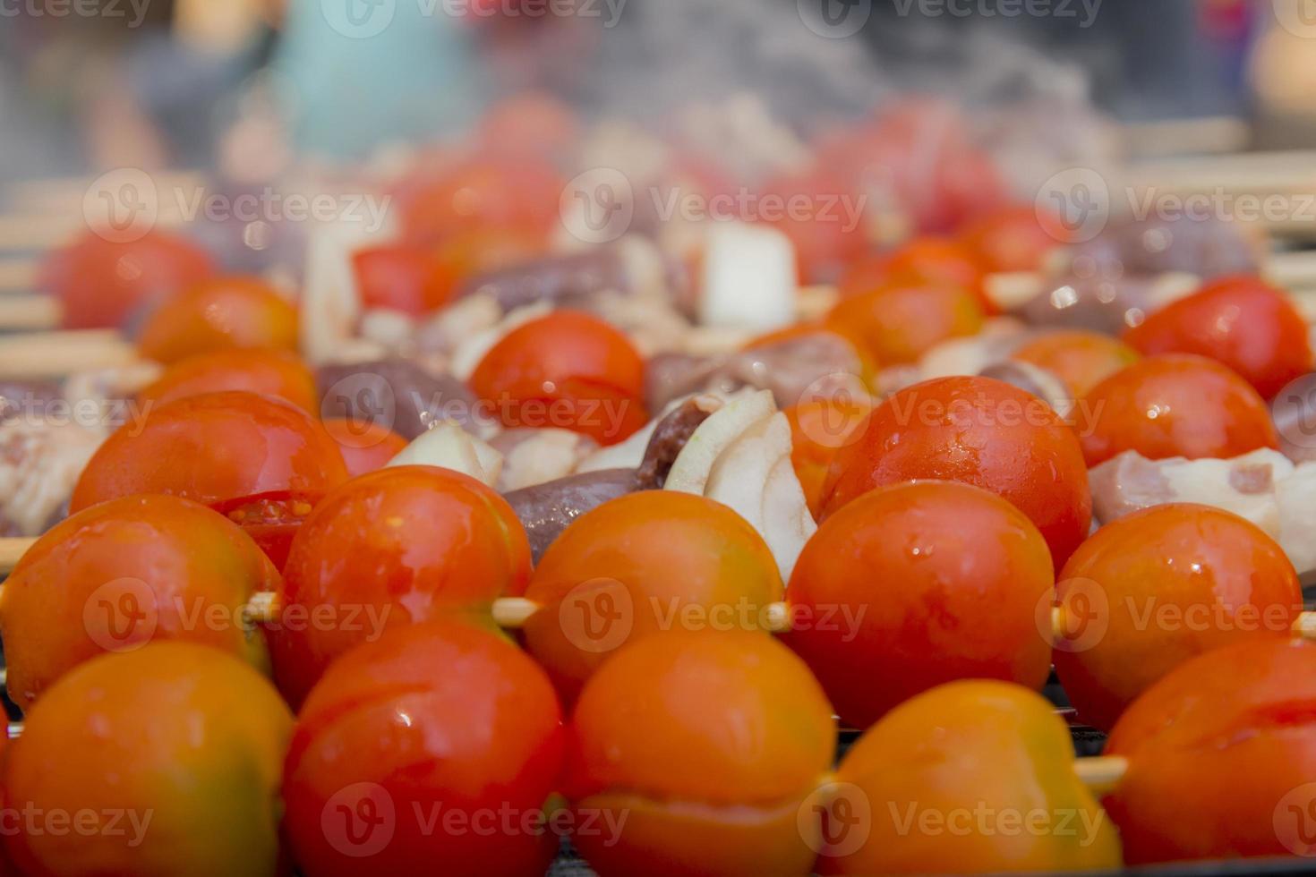 Chicken hearts with tomato and onion cooking on hot grill photo