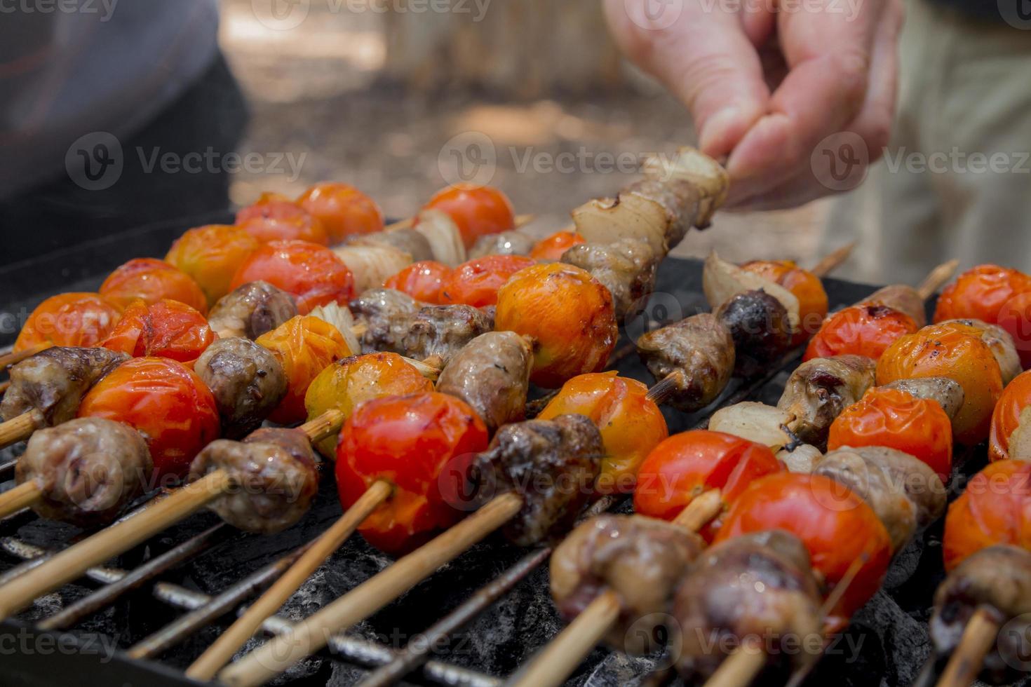 Chicken hearts with tomato and onion cooking on hot grill photo