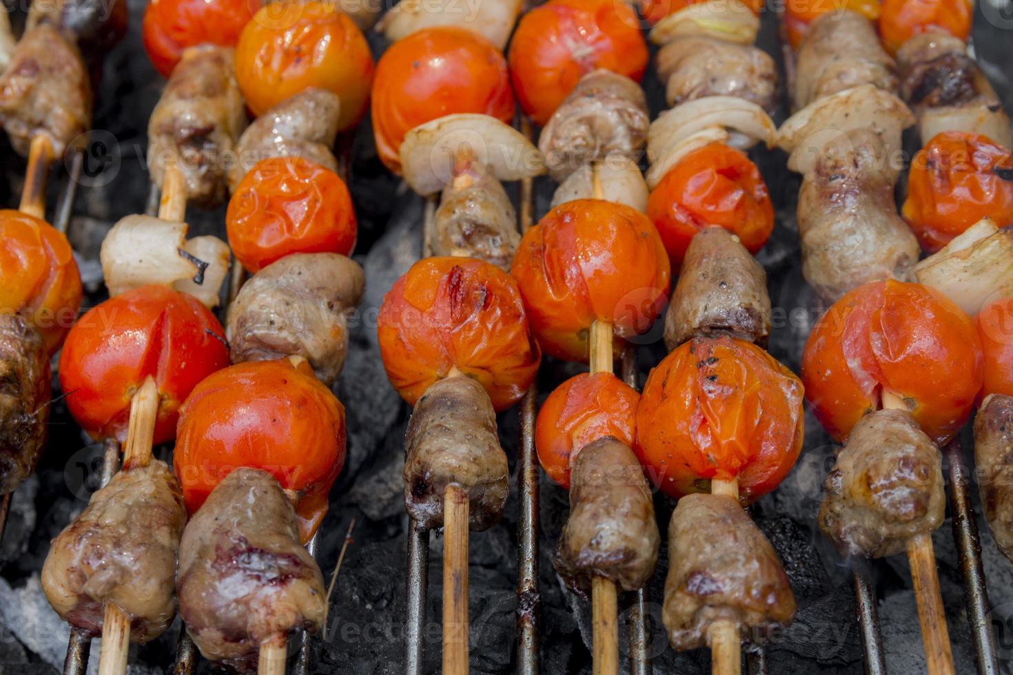 Corazones de pollo con tomate y cebolla cocinar a la parrilla caliente foto