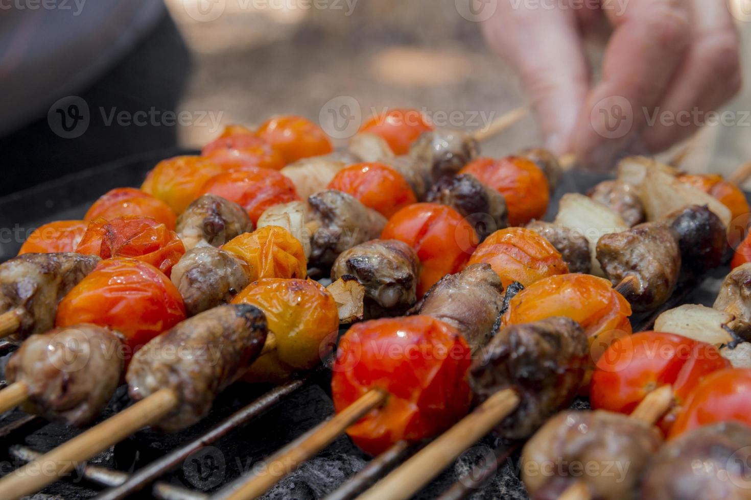 Chicken hearts with tomato and onion cooking on hot grill photo