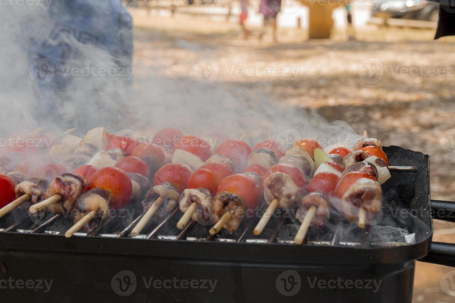 Chicken hearts with tomato and onion cooking on hot grill photo