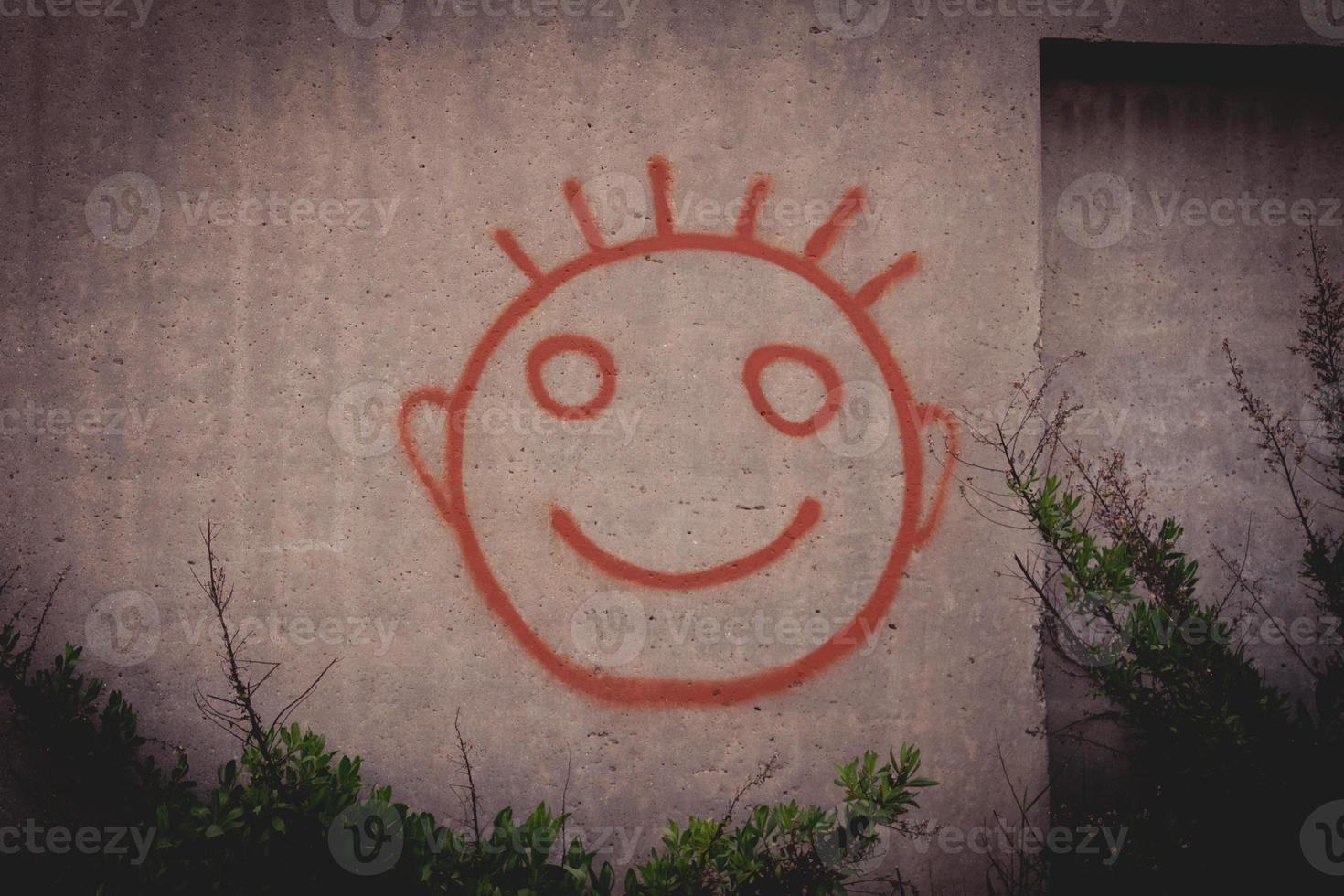 Graffiti painting of red happy smiley face on a concrete wall photo