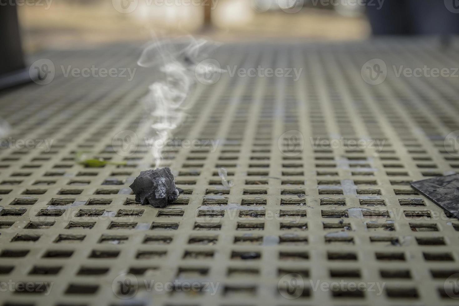 Smoke emitted from a piece of burnt wood coal on a metal table photo