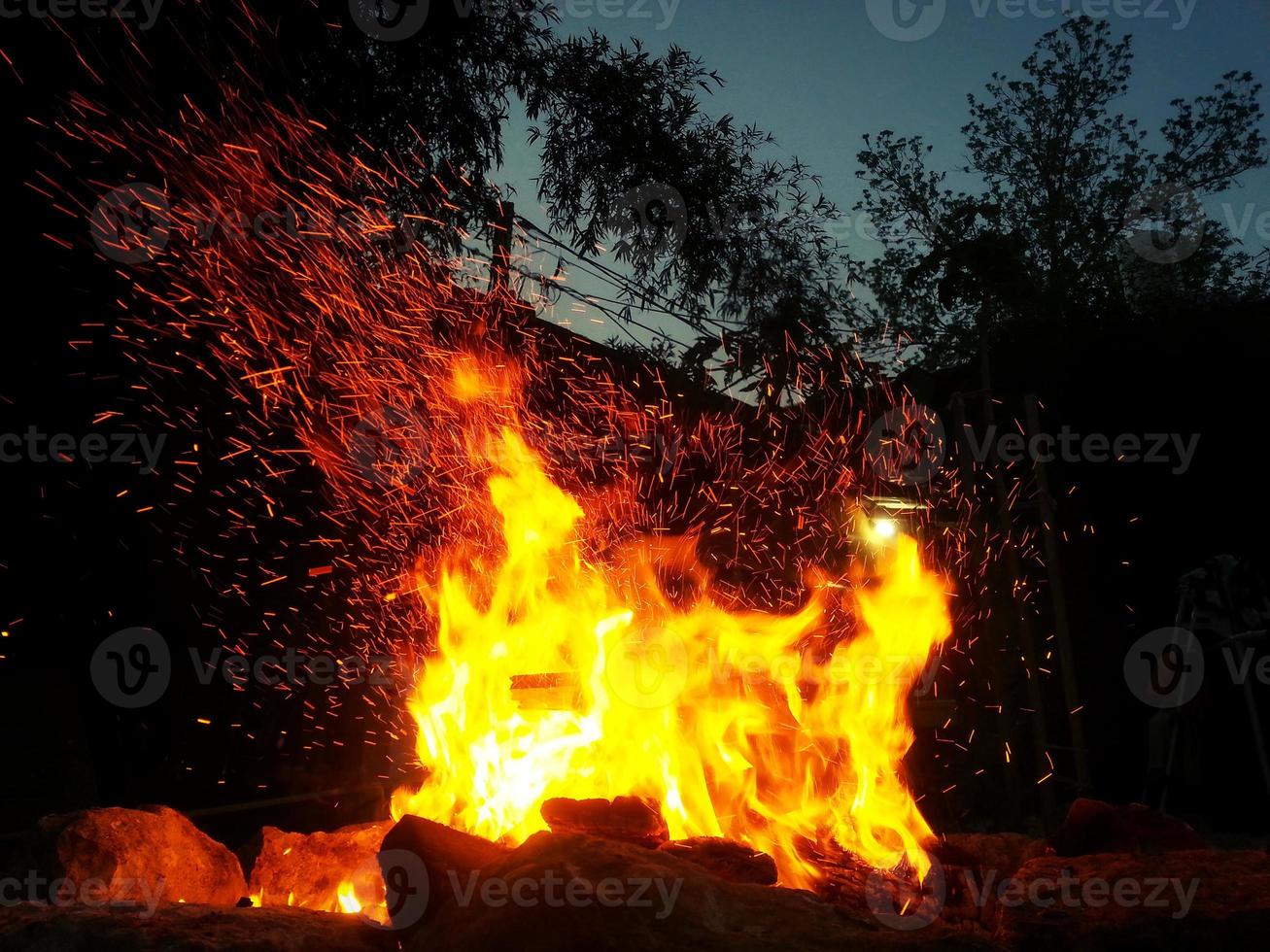 Las chispas rebotan en una hoguera por la noche después de que se arroja un tronco. foto