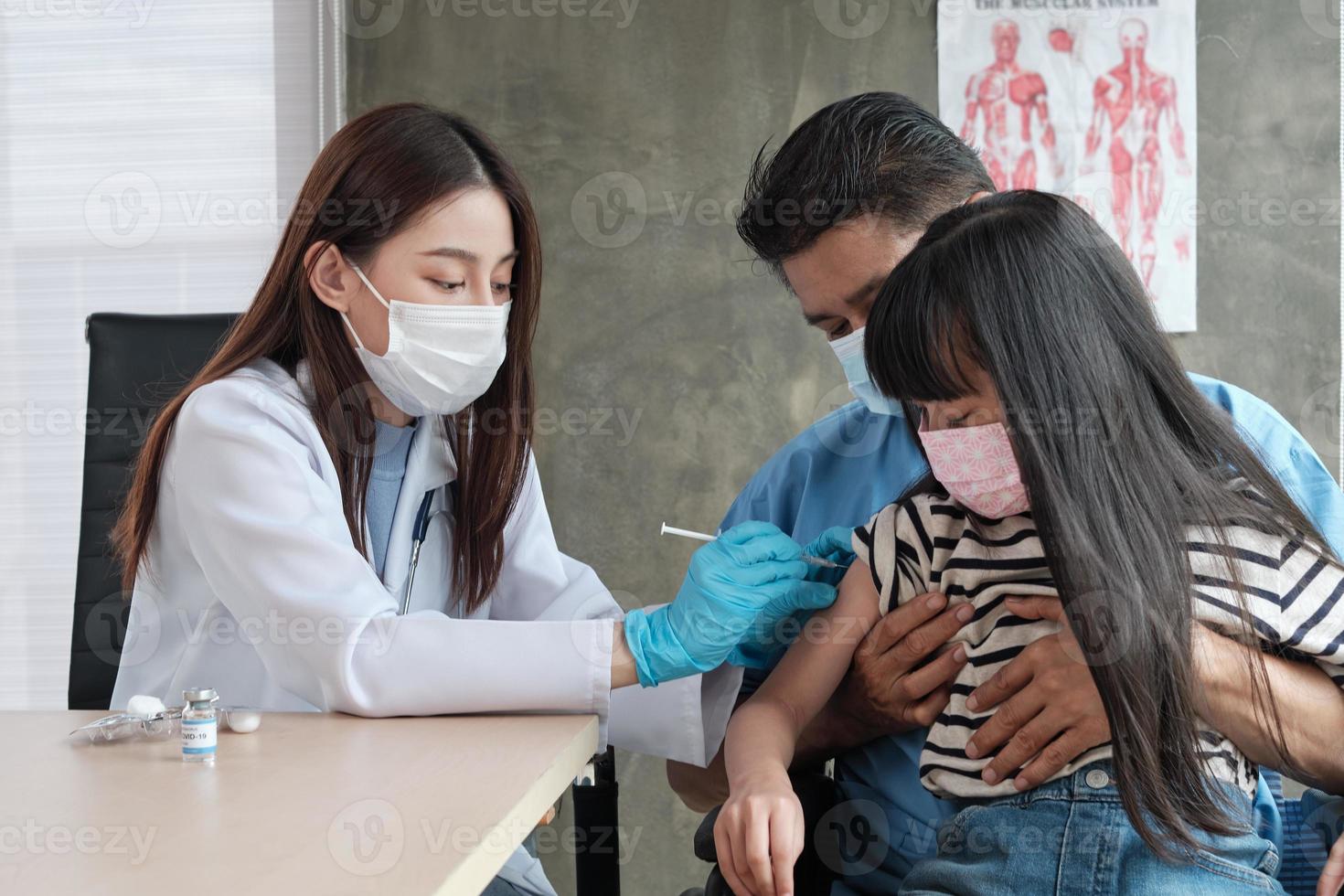 Doctora vacunando a una niña asiática en la clínica de pediatría. foto