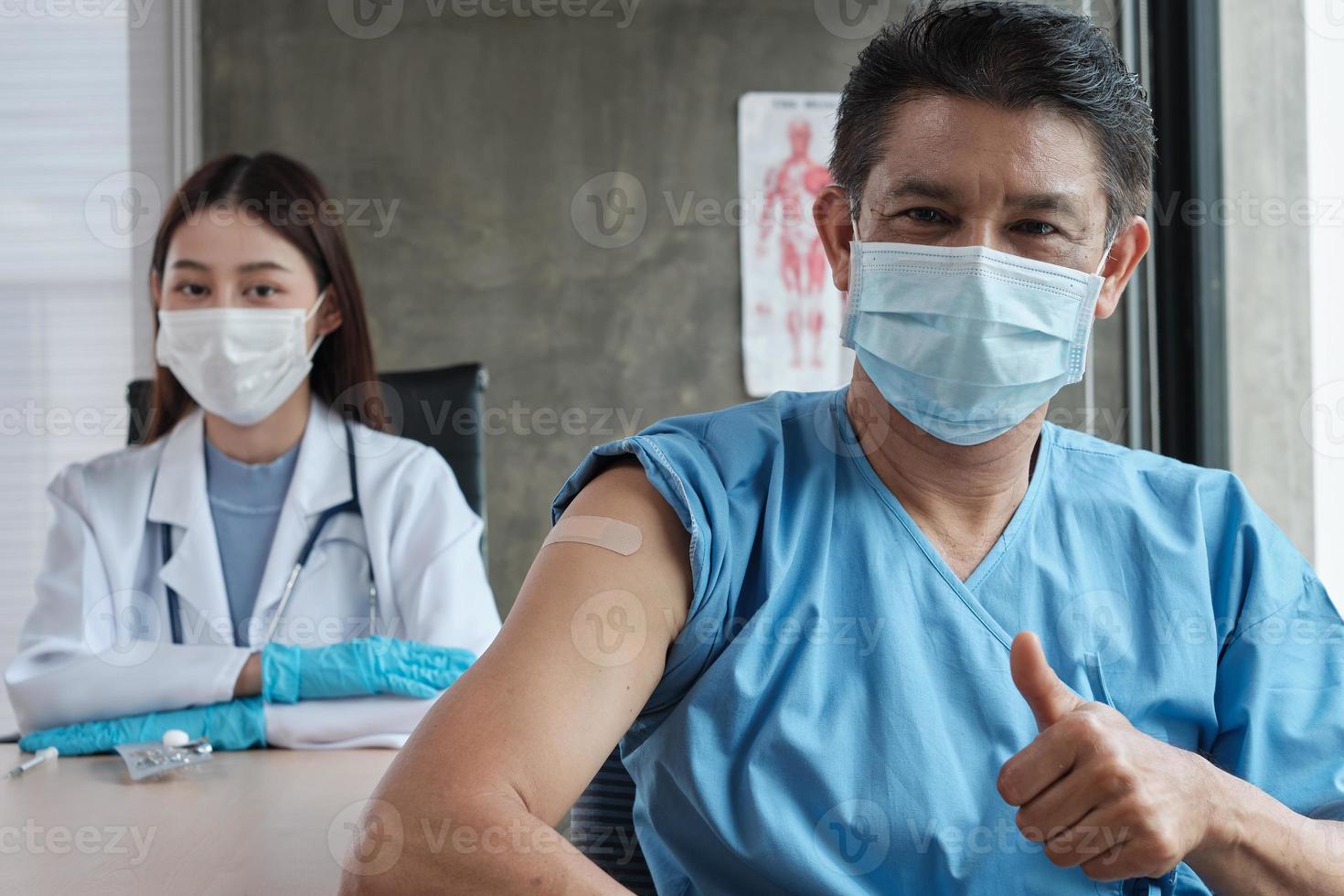 Paciente masculino asiático con mascarilla pulgar hacia arriba con una doctora. foto