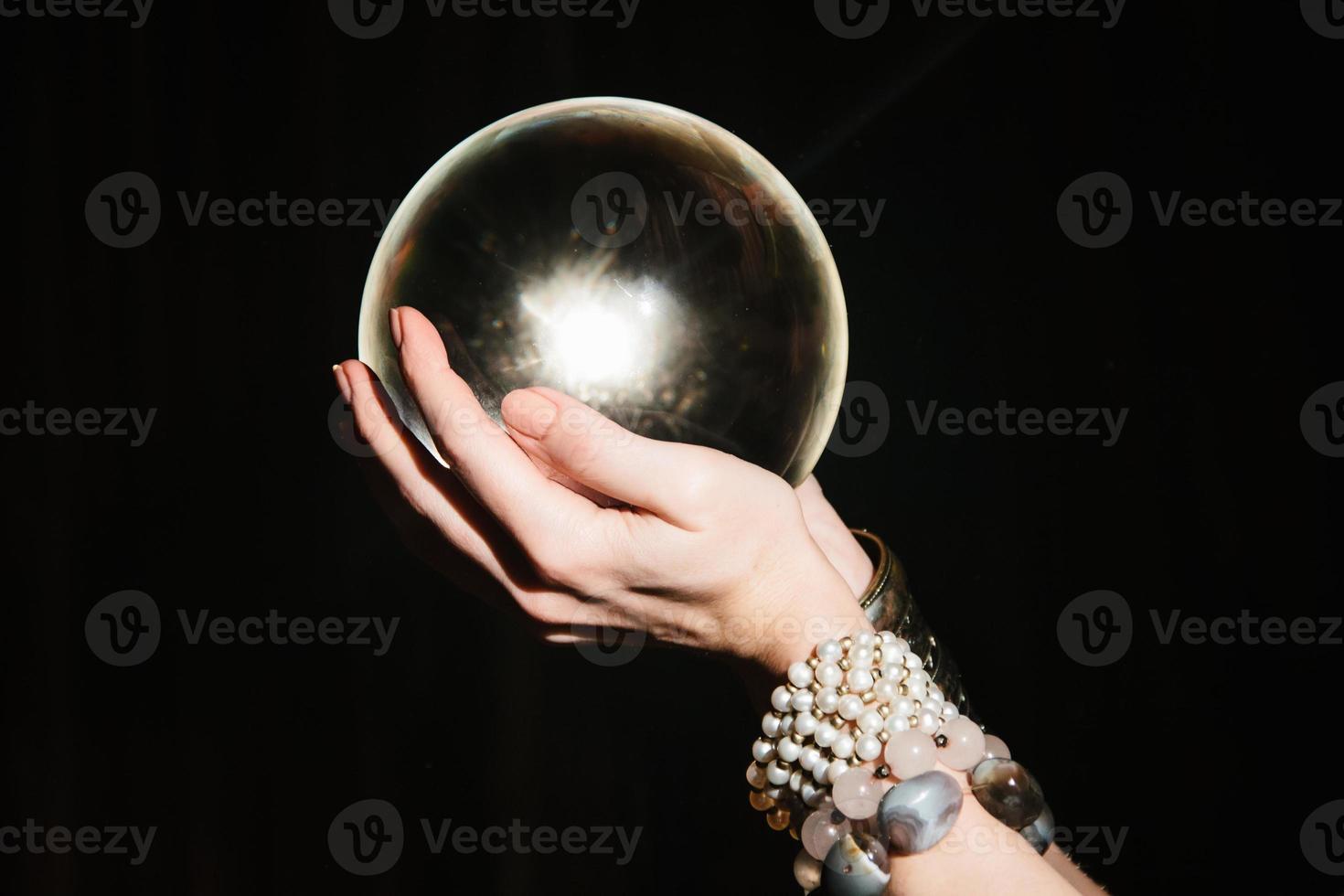 Fortuneteller's hands on a glass orb on black background. photo