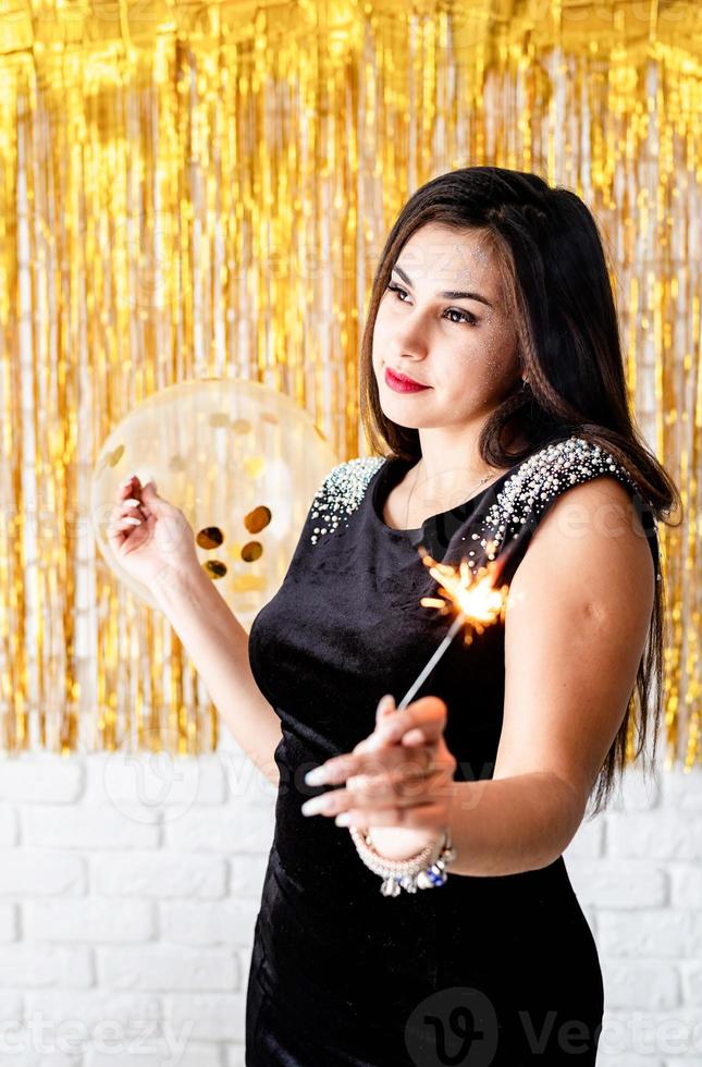 woman holding sparkler and balloon on golden background photo