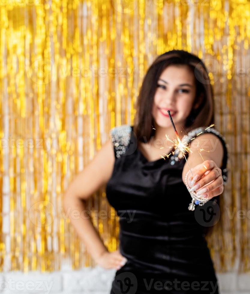 woman holding sparkler and balloon on golden background photo