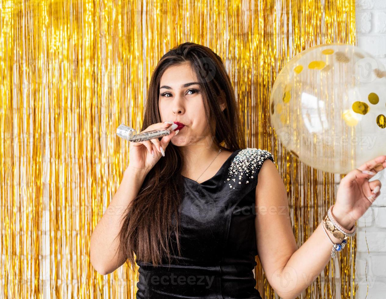 Mujer celebrando su cumpleaños soplando el hacedor de ruido foto