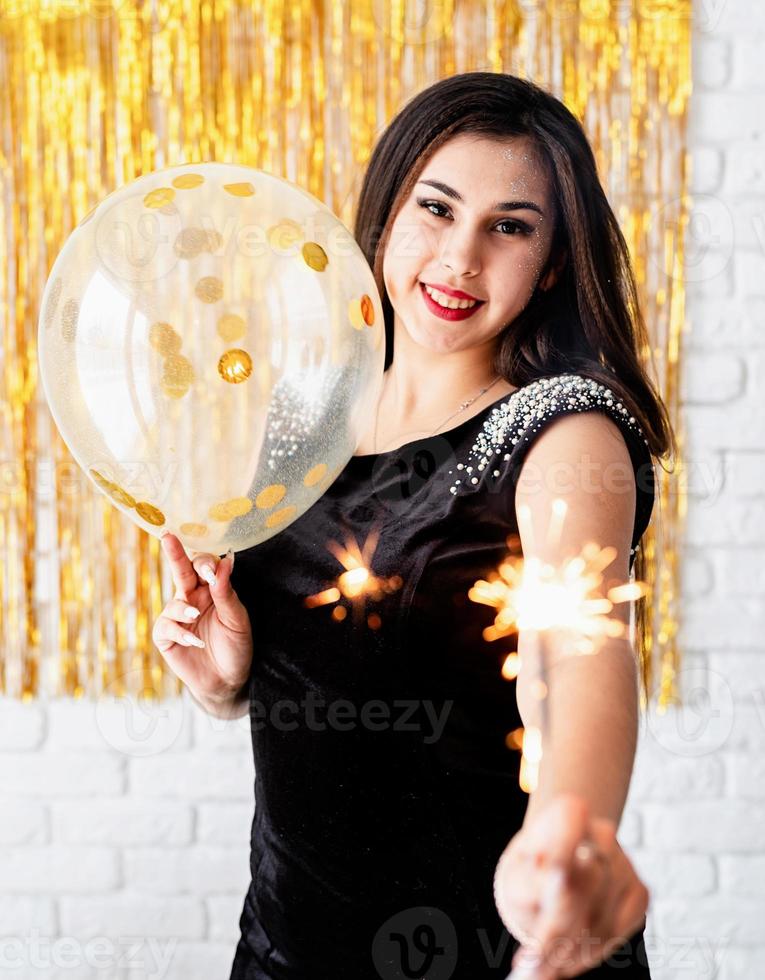 woman holding sparkler and balloon on golden background photo